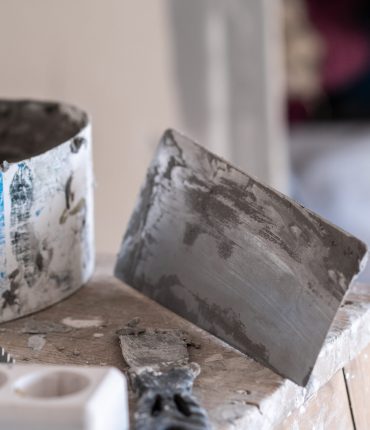 Applying decorative putty. White abstract texture of surface covered with putty. textured background of filler paste applied with putty knife in irregular dashes and strokes. Rough surface plaster